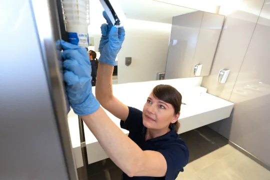 lady installing citron hygiene air freshener in washroom to improve indoor air quality